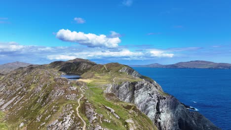 Lugares-épicos-De-Irlanda-Drones-Sobrevolando-El-Sendero-Hasta-El-Faro-De-Sheep&#39;s-Head-Con-Turistas-Caminando-Bajo-Un-Sol-Brillante,-Un-Paisaje-Espectacular-De-La-Forma-Salvaje-Del-Atlántico