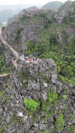 Vertical-video-aerial-of-the-rocky-side-of-Hang-Mua-Viewpoint,-Vietnam