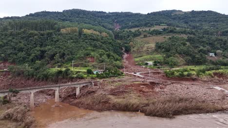 River-water,-road-bridge,-rural-slope,-littered-debris,-natural-disaster