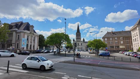 Tráfico-De-Coches-En-El-Centro-De-La-Ciudad-De-Angers-Con-La-Iglesia-Eglise-Saint-Laud-En-El-Fondo,-Francia