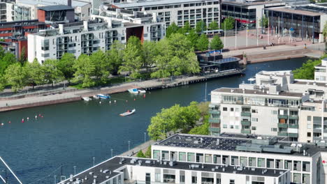 Telephoto-drone-shot-following-a-small-boat-on-the-Ruoholahti-canal,-spring-in-Helsinki