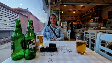 Enjoying-Mythos-beer-with-beautiful-girl-in-cafe-of-Athens,-motion-view
