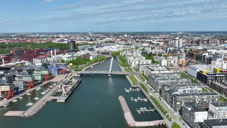 Drone-circling-the-Cruselli-bridge,-sunny,-summer-day-in-Ruoholahti,-Helsinki