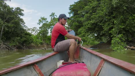 Man-navigates-a-motorized-boat-through-lush-greenery-on-a-calm-river-in-Florencia,-Colombia