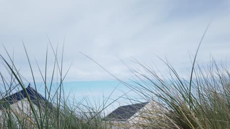 Blick-Auf-Das-Meer-Von-Sanddünengräsern-über-Strandhüttendächern-Southwold
