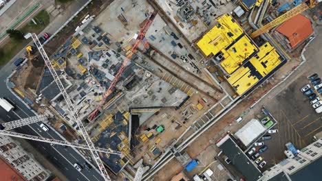 A-bustling-construction-site-with-cranes-and-yellow-structures-in-progress,-aerial-view