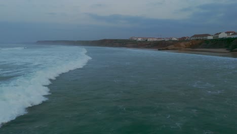 Aerial-drone-shot-tracking-a-wave-crashing-at-sunset-in-the-Baleal-Beach,-Portugal