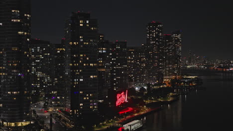 NYC-New-York-Aerial-v317-flyover-East-river-capturing-night-cityscape-of-waterfront-Hunters-Point,-featuring-illuminated-Pepsi-Cola-sign-at-recreational-park---Shot-with-Inspire-3-8k---September-2023