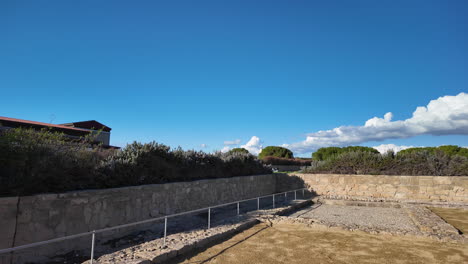 Ground-level-view-of-ancient-ruins-in-Pafos,-Cyprus,-showcasing-stone-walls-and-excavated-areas-under-a-bright-blue-sky