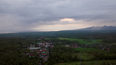 Gruesa-Capa-De-Nubes-En-El-Cielo-Sobre-La-Aldea-Tropical-Que-Emerge-De-La-Selva-En-Bali,-Aérea