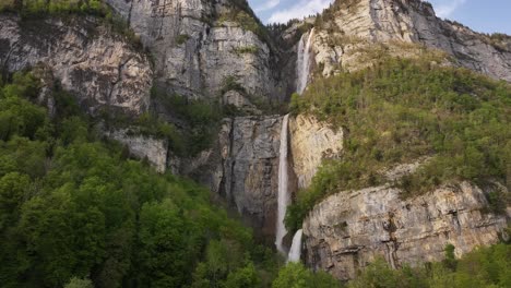 Seerenbach-Falls-showcases-three-cascading-waterfalls-flowing-down-a-rugged-cliff-surrounded-by-lush-greenery-in-the-Amden-municipality,-Switzerland