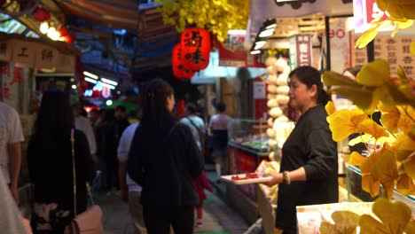 Los-Turistas-Deambulan-Por-Un-Encantador-Callejón-Lleno-De-Puestos-De-Comida-Y-Tiendas-De-Recuerdos-Dentro-De-La-Antigua-Calle-Jiufen,-Vendedores-Que-Ofrecen-Muestras-Y-Degustaciones-De-Comida,-Un-Punto-Turístico-En-Taiwán.