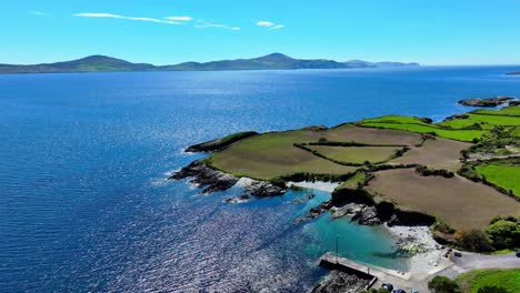 Drone-Pequeño-Puerto-Pesquero-Protegido-Mar-Azul-Y-Cielo-Con-Península-Montañosa-West-Cork-Irlanda,-Península-De-Cabeza-De-Oveja-En-El-Camino-Atlántico-Salvaje