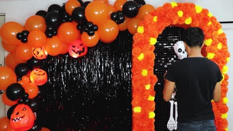 Hombre-Latino-Decorando-Para-El-Día-De-Muertos-Con-Globos-Y-Esqueleto