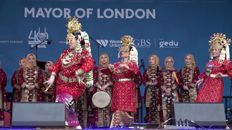 Indonesische-Tänzer-In-Traditionellen-Roten-Outfits-Und-Goldenen-Kopfbedeckungen-Tanzen-Auf-Der-Bühne-Auf-Dem-Trafalgar-Square,-Dem-Jährlichen-Eid-Festival-Des-Bürgermeisters-Von-London