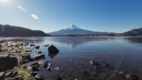 Mt-Fuji-showing-the-snow-mountain-with-snow-on-its-peak-and-a-clear-reflection-in-the-water-of-the-lake-in-front-of-it-on-sunny-clear-sky-day-in-Japan