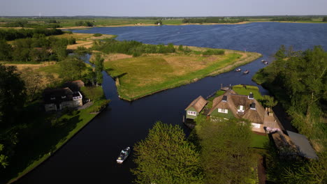 Boats-sailing-through-canal-into-lake-in-Giethoorn,-aerial-drone-view