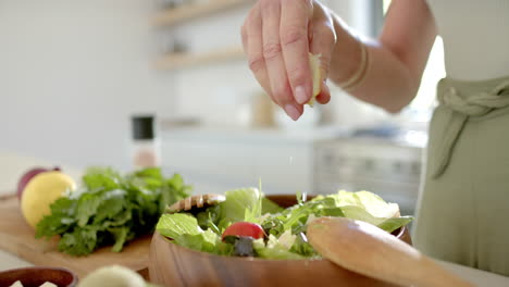 Una-Persona-Añadiendo-Condimentos-A-La-Ensalada-En-Una-Cocina-Luminosa