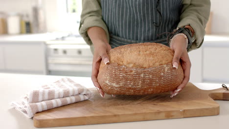 African-American-young-woman-holding-freshly-baked-bread-on-wooden-board