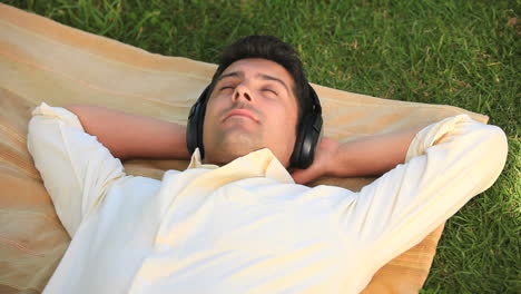 Man-relaxing-listening-to-music-outdoors