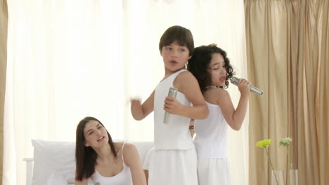 Family-singing-and-dancing-on-bed-with-microphones