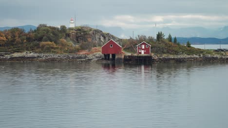 Tidy-cottage,-boathouse,-and-a-small-lighthouse-on-the-small-island-on-the-rocky-coast-of-Lofoten