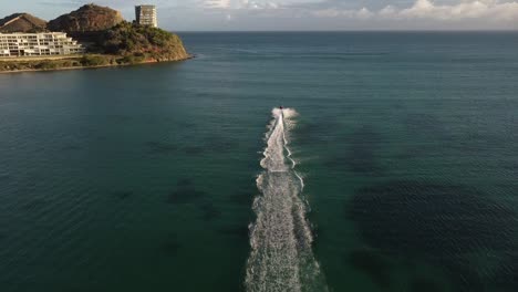 Aerial-tracking-shot-of-jet-ski-speeding-on-sea-along-coastline-of-Isla-de-Margarita,-Venezuela