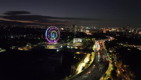 Aerial-view-approaching-the-illuminated-Aztlan-Park,-nighttime-in-Mexico-city