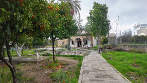 Un-Camino-Que-Conduce-A-Una-Mezquita-En-Nicosia,-Chipre,-Rodeado-Por-Un-Jardín-Con-Naranjos-Y-Otras-Zonas-Verdes.
