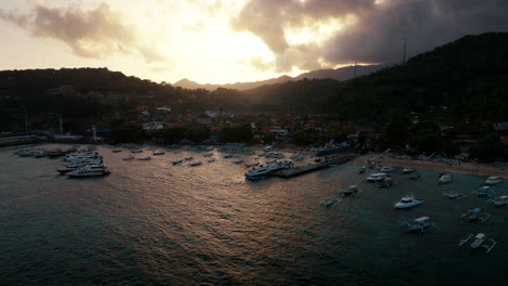 Yachts-moored-at-Pantai-Padang-Bai-at-sunset,-Bali-in-Indonesia