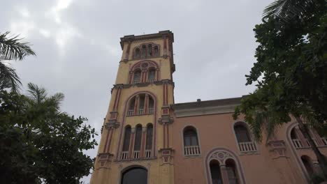 Historic-university-building-in-Cartagena,-Colombia-with-a-pink-facade-and-palm-trees-in-view