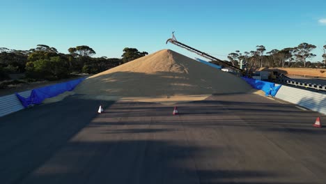 Aerial-backwards-flight-showing-heap-of-grains-at-harvest-industrial-factory-in-Australia