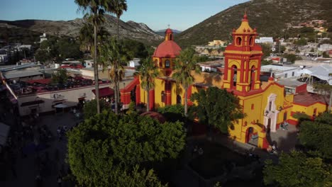 Iglesia-En-Un-Pequeño-Pueblo-Mexicano,-Con-Colores-Vibrantes-Y-El-Paisaje-Desértico-De-Fondo,-Mostrando-El-Típico-Estilo-De-Casa-Regional-Y-Un-Contraste-De-Luces-Y-Sombras.