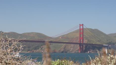 Puente-Golden-Gate-En-San-Francisco-Con-Un-Barco-Blanco-Pasando,-Tiro-De-ángulo-Bajo-Desde-Crissy-Field-South-Beach,-California,-Estados-Unidos