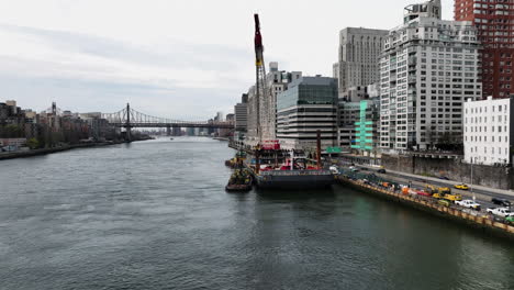 Vista-Aérea-Volando-Alrededor-De-Una-Grúa-Pesada-Flotante-Montada-En-Una-Barcaza-En-East-River,-Nueva-York