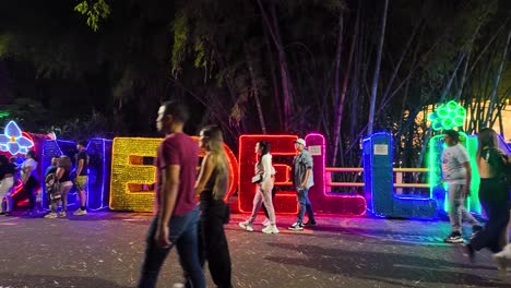 Vida-Nocturna-En-El-Poblado-De-Medellín,-Con-Gente-Disfrutando-Del-Cartel-Iluminado-De-&quot;Medellín&quot;-En-Provenza