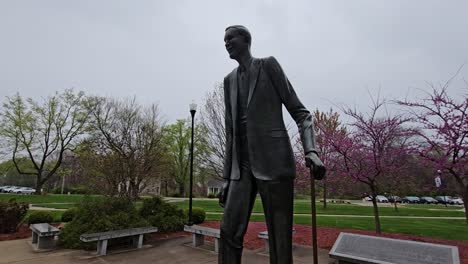 Ein-Heiterer-Frühlingsmorgen-In-Einem-Campuspark-Mit-Einer-Markanten-Statue,-Umgeben-Von-Blühenden-Bäumen-Und-Bänken,-Die-Eine-Friedliche-Atmosphäre-Für-Einen-Spaziergang-Schaffen