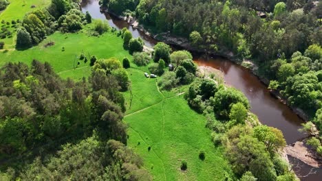 Un-Exuberante-Paisaje-Forestal-Verde-Con-Un-Río-Sinuoso-En-Un-Día-Soleado,-Vista-Aérea