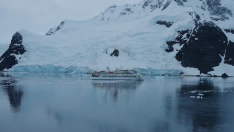 Expedition-cruise-ship-passing-large-iceberg-in-Antarctica