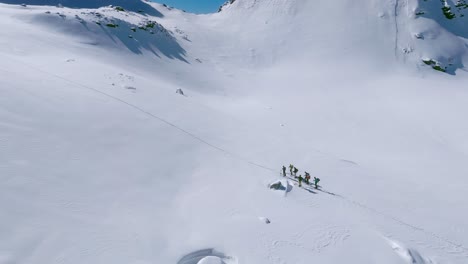 Hikers-traverse-the-vast-snowy-landscape-of-Cima-Cece,-aerial-view