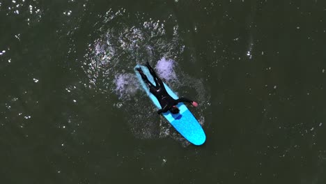 Eine-Draufsicht-Auf-Einen-Surfer,-Der-An-Einem-Sonnigen-Tag-Auf-Seinem-Brett-Im-Meer-Paddelt