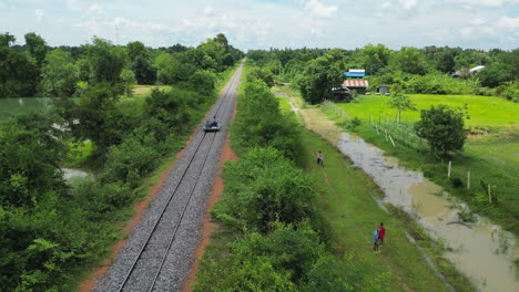 Mit-Der-Bambusbahn-Durch-Ländliches-Ackerland-In-Der-Nähe-Von-Battambang,-Kambodscha.-Drohnenverfolgung-Von-Hinten