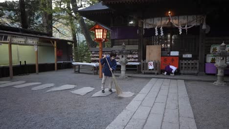 Japanese-woman-sweeping-temple-entrance-with-traditional-Japanese-broom