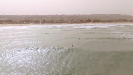 Surfers-waiting-for-waves-in-Giulianova-sandy-beach-close-to-the-port-at-misty-day