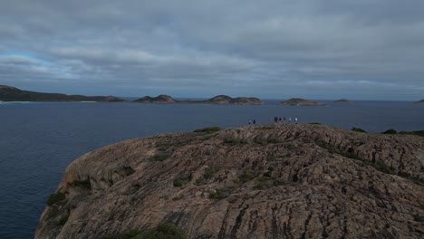 Group-Of-People-Enjoying-Ocean-Breeze-On-Top-Of-Hill,-Cape-Le-Grand-Area,-Western-Australia