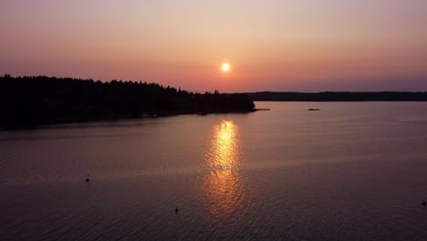 Sunset-in-Stockholm-Archipelago-with-golden-light-reflecting-on-water,-aerial-view