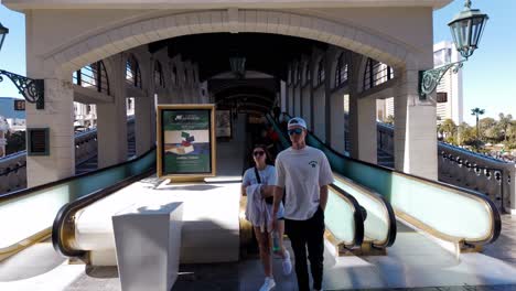 People-walking-down-an-outdoor-escalator-in-Las-Vegas,-featuring-elegant-architecture-and-sunny-weather