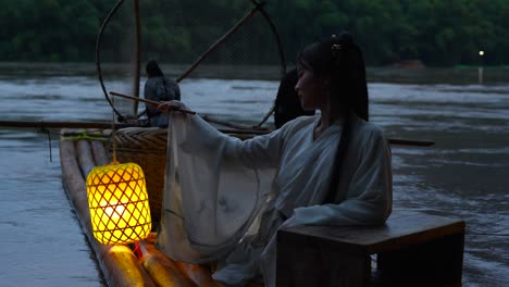 Hanfu-girl-holding-an-illuminated-lantern-on-a-bamboo-raft-with-Cormorant-birds-at-night