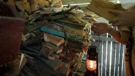 A-Woman-Utilizes-an-Old-Vintage-Kerosene-Lantern-While-Collecting-Firewood-From-the-Stack---Close-Up