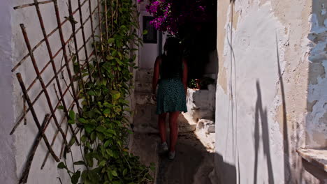 Girl-with-sundress-and-long-black-hair-walks-in-narrow-street-of-Anafiotika,-Athens,-Greece